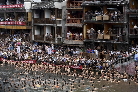 2018年6月18日，湖南湘西凤凰古城的沱江河上演抢鸭子大战，众多居民与游客纷纷跳入河中，争抢从吊脚楼上抛下的鸭子，以此方式庆祝端午节的到来。图/视觉中国