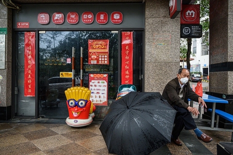 2020年2月13日，广东广州，一名男子在关门的商铺前休息。春节假期结束，广州街头一些商铺依旧关门，未见开门营业。