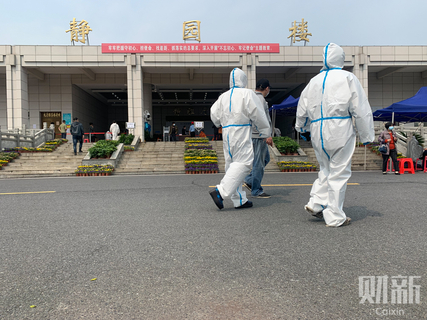 2020年3月26日下午，武汉汉口殡仪馆，身着防护服的工作人员走过。当天上午，排队亲属从汉口殡仪馆静雅厅的大门口一直蜿蜒延伸至东侧乾和厅的门前，有近200米长。 图/财新记者 丁刚