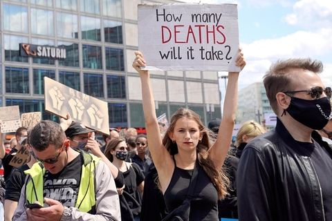 当地时间2020年6月6日，德国柏林，一名示威者举着“种族主义还要造成多少死亡”的标语。当日，约1.5万人聚集在柏林亚历山大广场举行示威，纪念在美国警察暴力执法中丧生的乔治•弗洛伊德，抗议种族主义和警察暴力。图/人民视觉