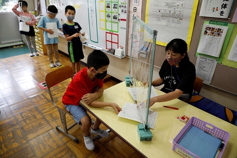 当地时间2020年7月16日，日本船桥市，当地小学生做好防护措施返校上课，老师与学生隔透明挡板交流。图/视觉中国
