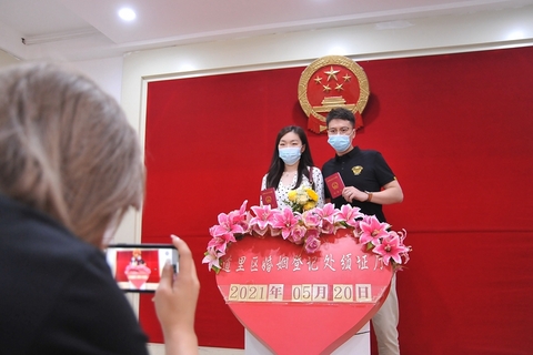 2021年5月20日，哈尔滨，新人们戴着口罩登记结婚。“520”被赋予了“我爱你”的含义，因此成为许多新人领取结婚证的首选日子。图/视觉中国