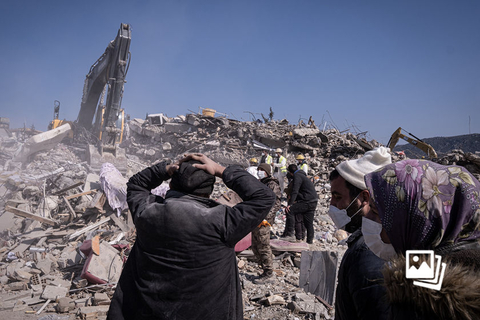 当地时间2023年2月12日，土耳其哈塔伊，在倒塌的楼房废墟旁，一名男子焦急地等待，期盼奇迹的发生。据土耳其和叙利亚的政府及救灾机构公布的数据，强震已造成两国超过3.3万人遇难。土耳其有至少6000栋建筑物在这次强震中倒塌或受损，救灾工作仍在进行之际，土耳其当局开始向部分倒塌建筑的建筑商发出拘捕令，有12人被捕。图：Ugur Yildirim/视觉中国